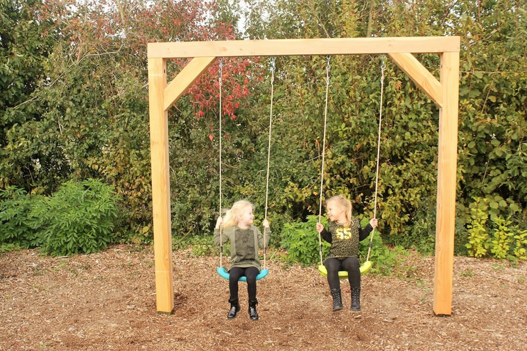 Schommelende kinderen op schommelzitje aan houten douglas frame