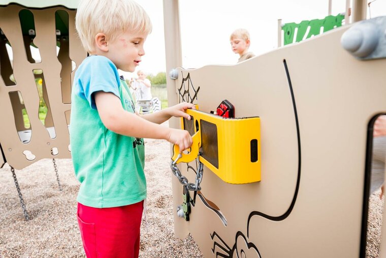 sfeerfoto van een speelpaneel van de Ledon Speeltoren Explore Fen Openbaar waarmee een kind in de speeltuin speelt