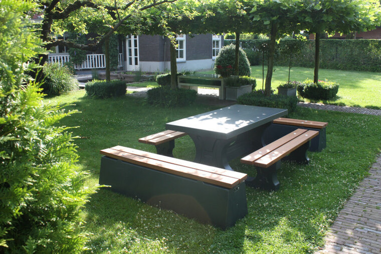 Betonnen Picknickset DeLuxe met Bamboe Zitvlak en Antraciet Gelakt met antracieten banken in een tuin