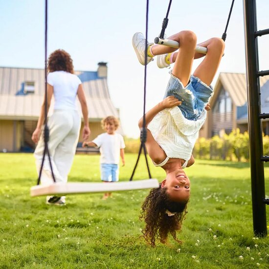 Meisje schommelt ondersteboven aan trapeze van berg