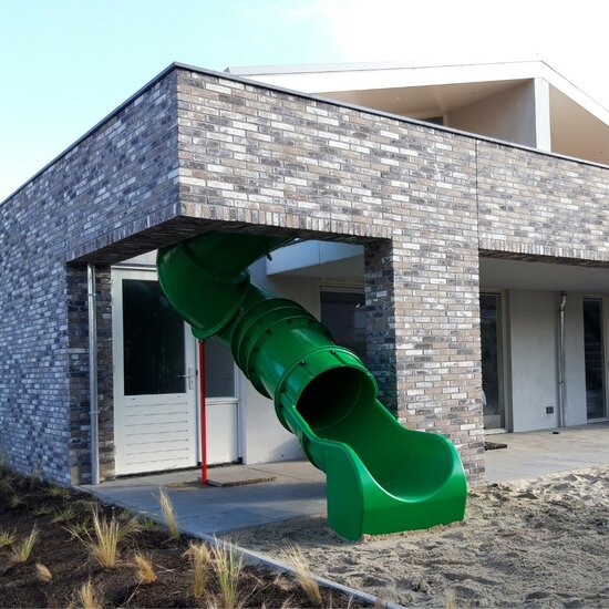 Maatwerk glijbaan groen aan gebouw