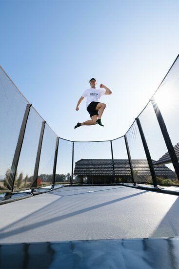man springt op Akrobat Trampoline Primus Challenger PLUS 330x250 cm met veiligheidsnet