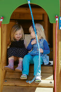 sfeerfoto van 2 kindjes die in de opening van het klimstukje van het Europlay Speeltoestel Blauwbaard zitten