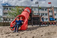 sfeerfoto van het uiteinde van de Kunststof buisglijbaan Openbaar Gebruik kleur rood, geplaatst op een speelplaats