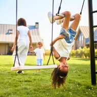 Meisje schommelt ondersteboven aan trapeze van berg