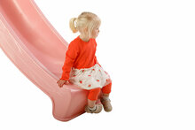 meisje zit op uiteinde pastel roze glijbaan